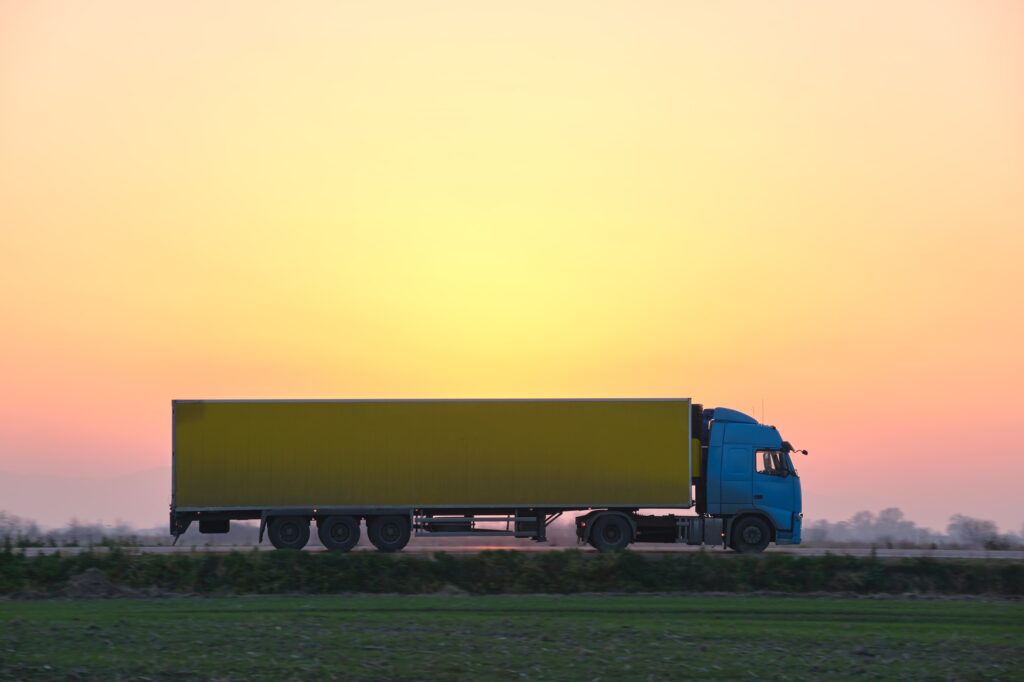Semi-truck with cargo trailer driving on highway hauling goods in evening. Delivery transportation